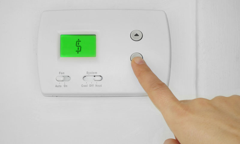 A thermostat where the temperature is a money sign and the person is pushing down. Learn how to make your heating system more efficient. | SHW Blog