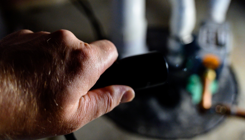 A man holds a flashlight over a sump pump. | SHW Blog