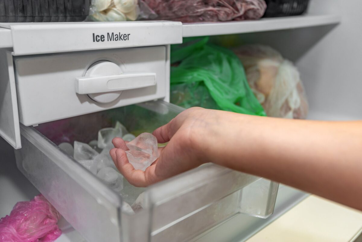 Hand taking ice from a refridgerator ice maker | SHW Blog