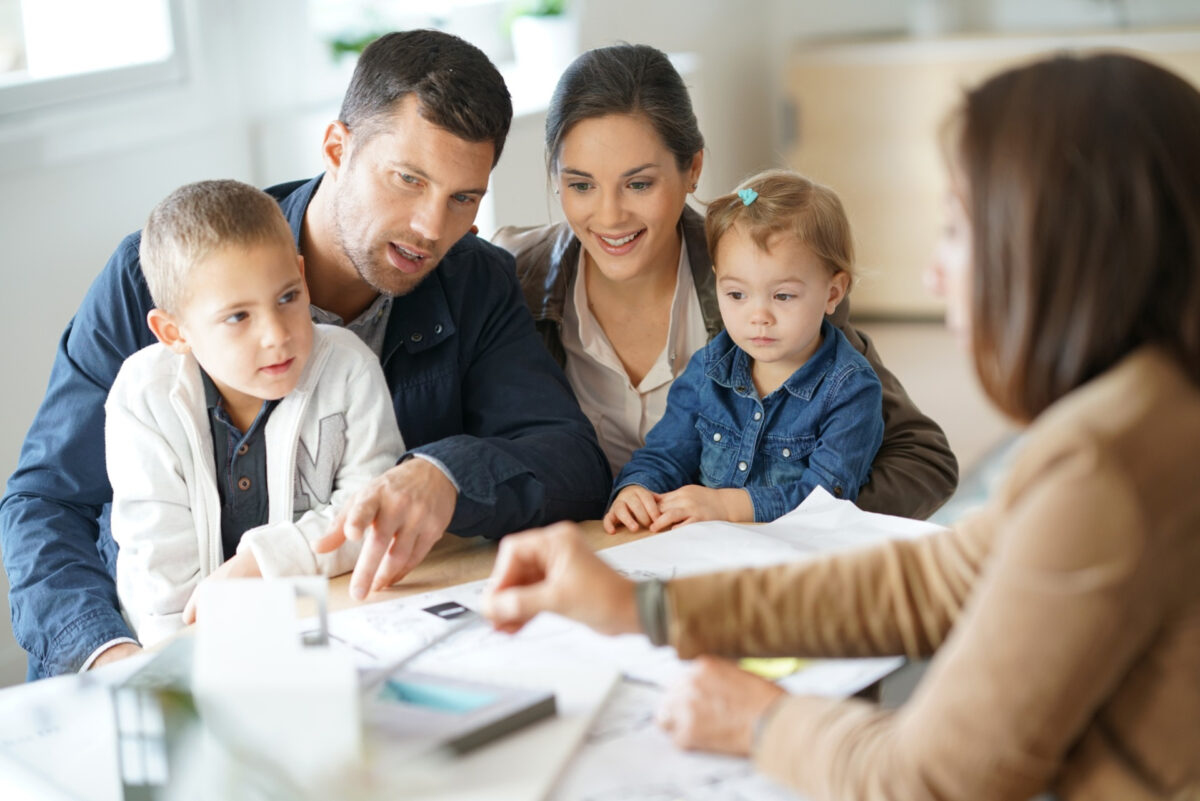 Family discussing new home options with real estate agent.