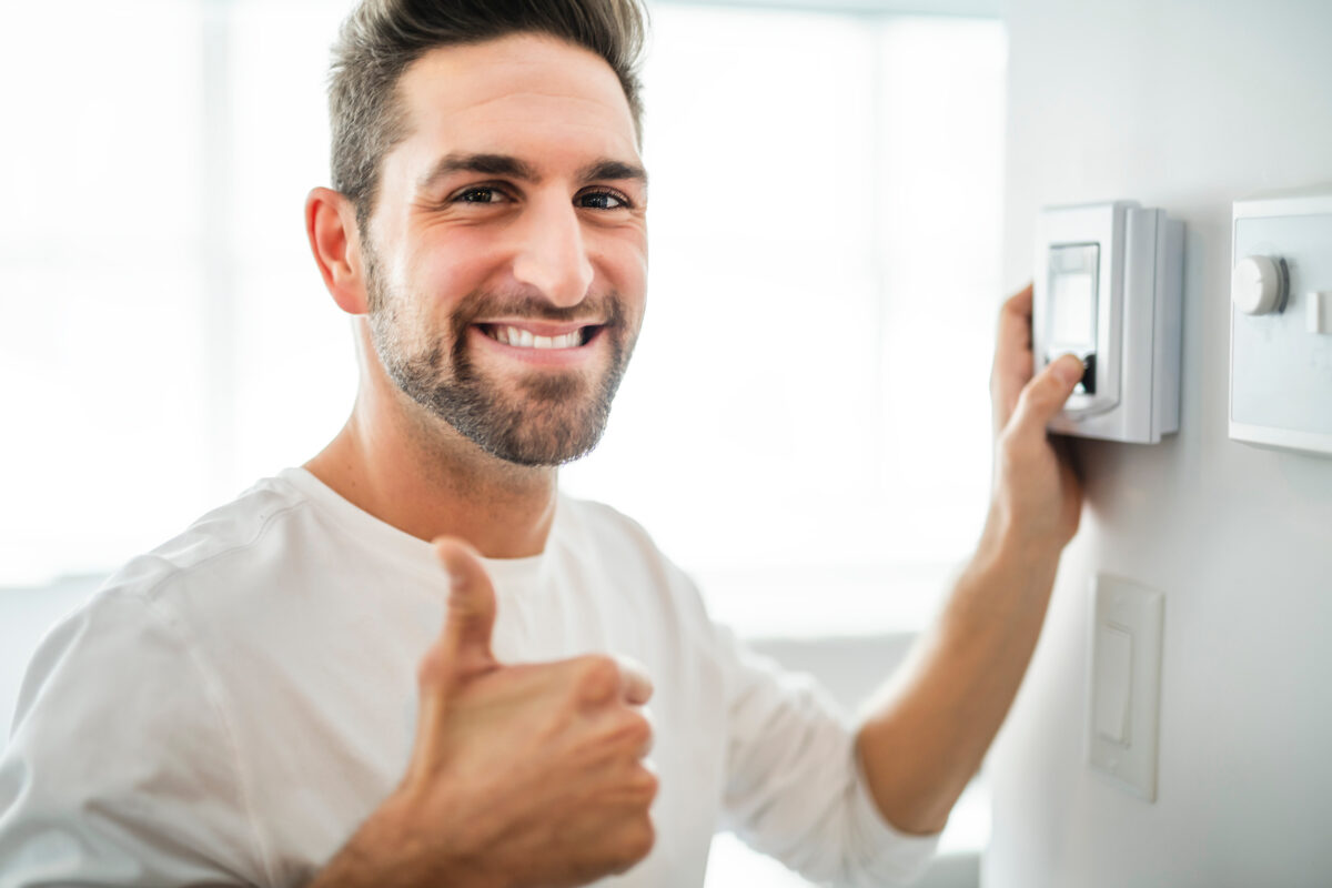 Cheerful man successfully troubleshooting problems with his thermostat.