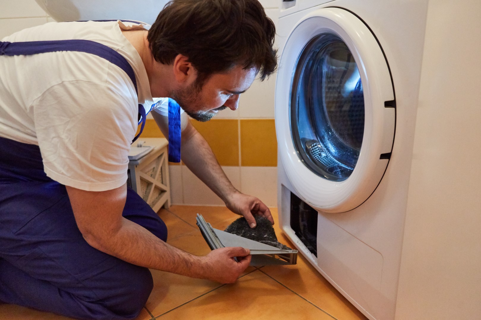 Professional repairman working on a broken clothes dryer.