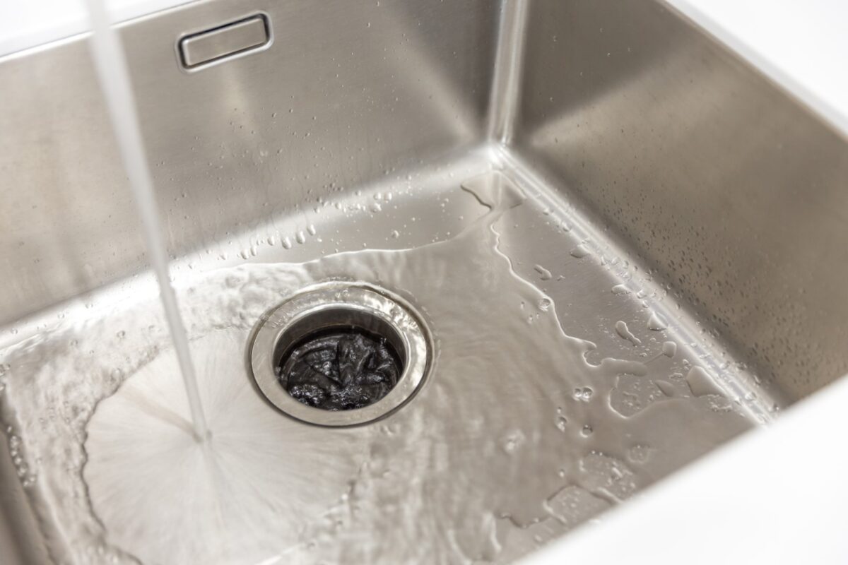 Very clean stainless steel kitchen sink with a garbage disposal. Running cold water.