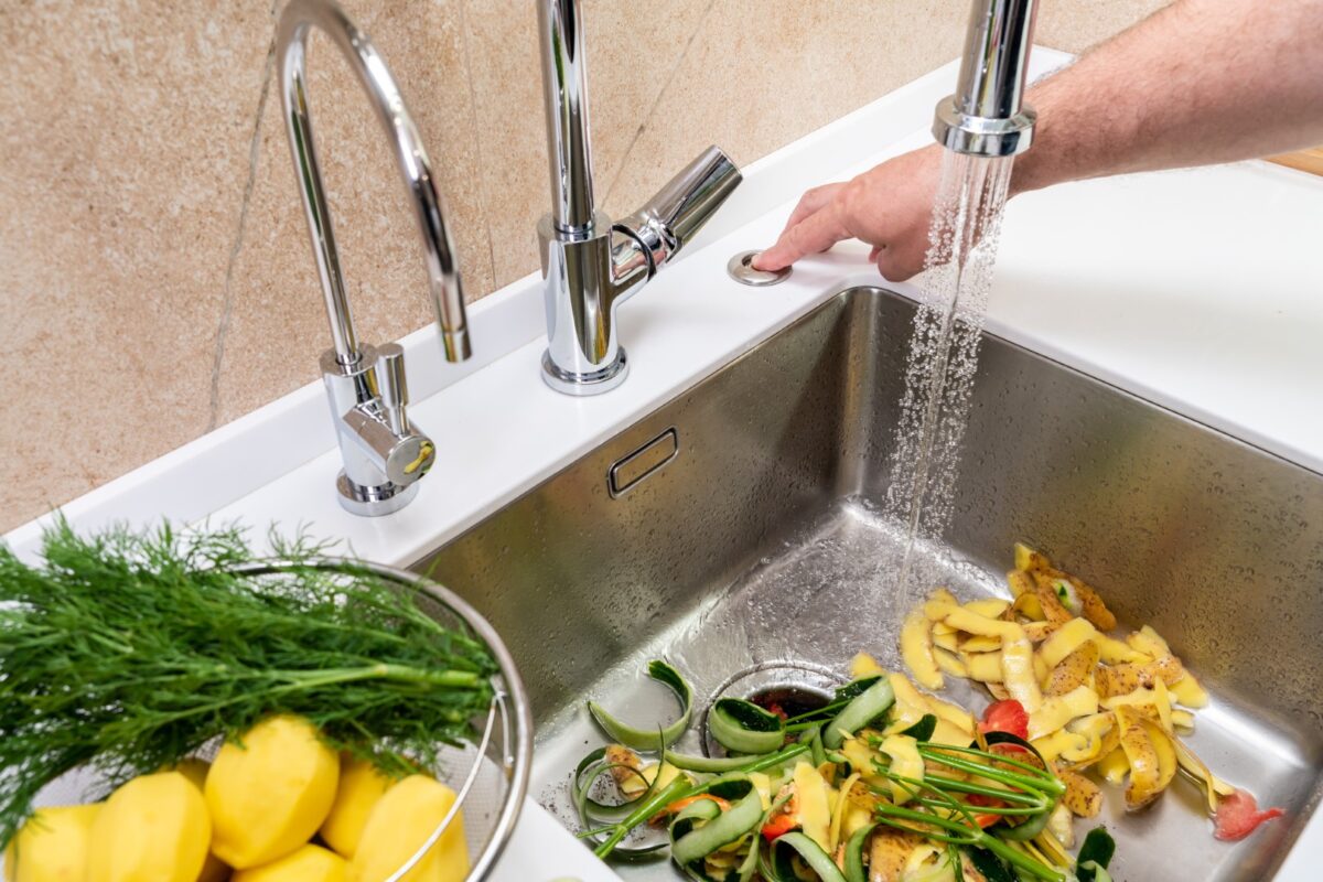 Man using a garbage disposal to get rid of vegetable food waste.