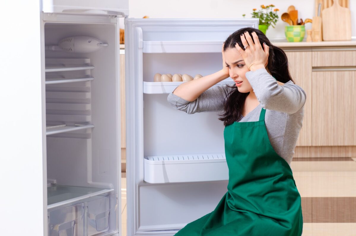Distraught woman dealing with refirgerator problems.