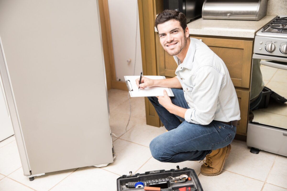 Appliance repairman fixing a fridge.
